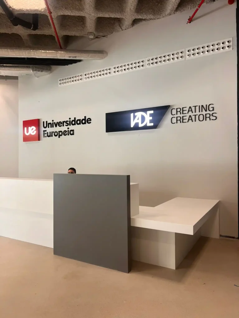 Recepción moderna de oficina con muebles minimalistas en tonos blanco y gris, y letreros iluminados.