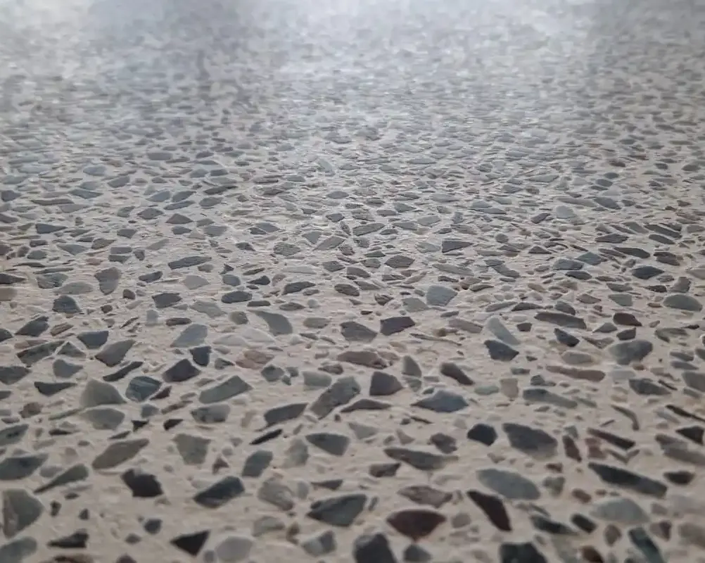 Primer plano de un suelo de terrazzo con piedras naturales en tonos grises, beige y marrones.
