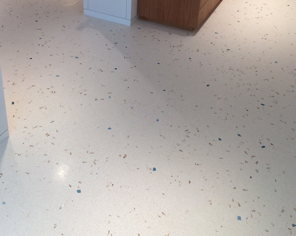 Piso de terrazo blanco con fragmentos azules y beige, en un entorno moderno.