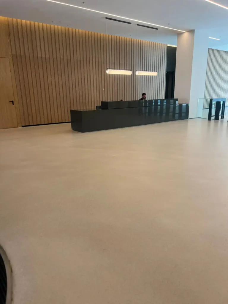 Oficina con recepción minimalista, mostrador negro y pared de madera con luces colgantes.