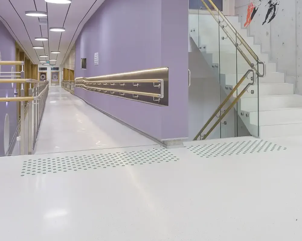 Pasillo moderno con paredes moradas, iluminación LED y escaleras blancas en diseño accesible.