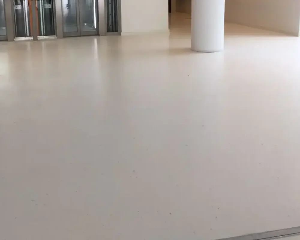 Piso de microterrazzo blanco brillante en área de acceso con ascensores.