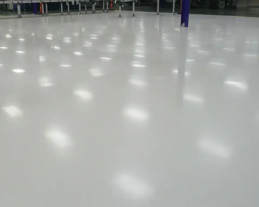 Piso blanco brillante en un espacio industrial con reflejos de luz en el suelo.
