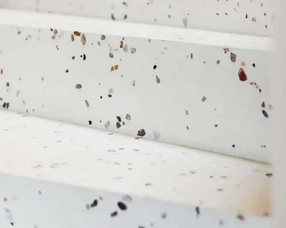 Escalera con peldaños de terrazo blanco y detalles de piedras