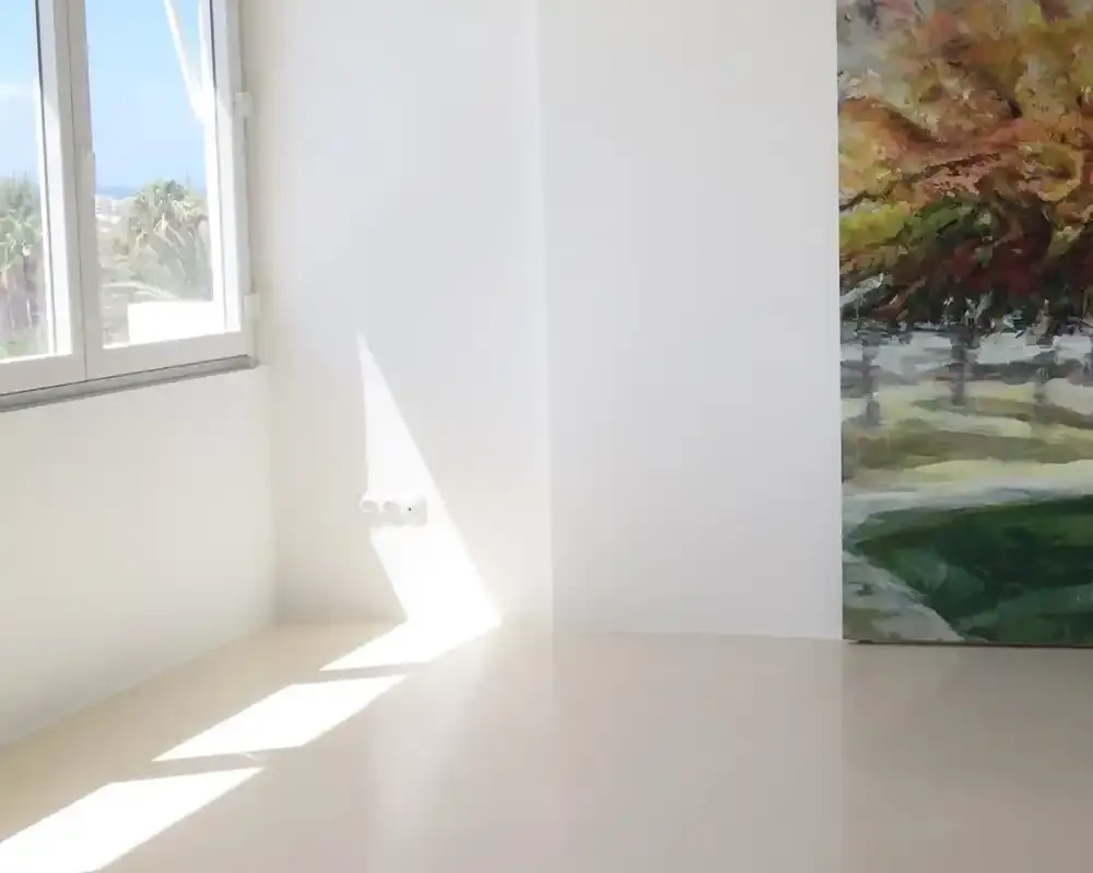 Sala luminosa con suelo de terrazo y pintura de paisaje en la pared.