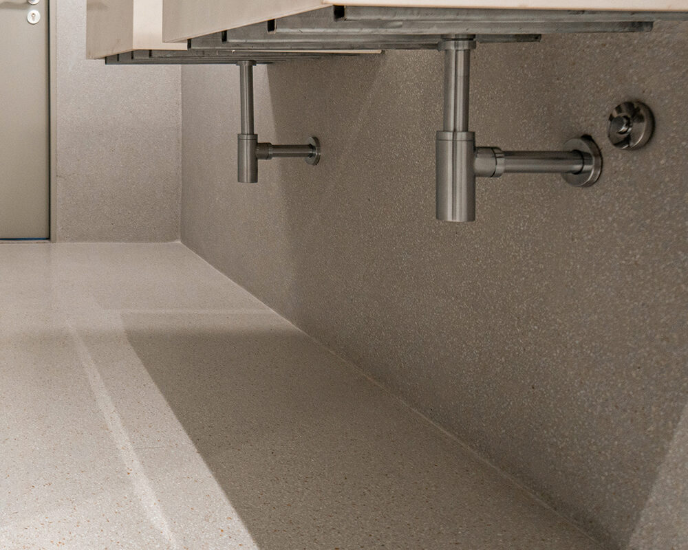 Baño moderno con pavimento cementoso decorativo tipo terrazo en el suelo y paredes.