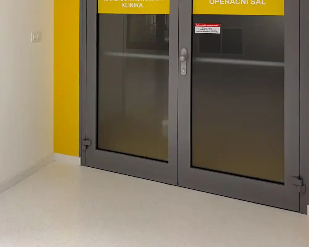 Pavimento cementoso decorativo blanco en pasillo de hospital con puerta de acceso a quirófano.