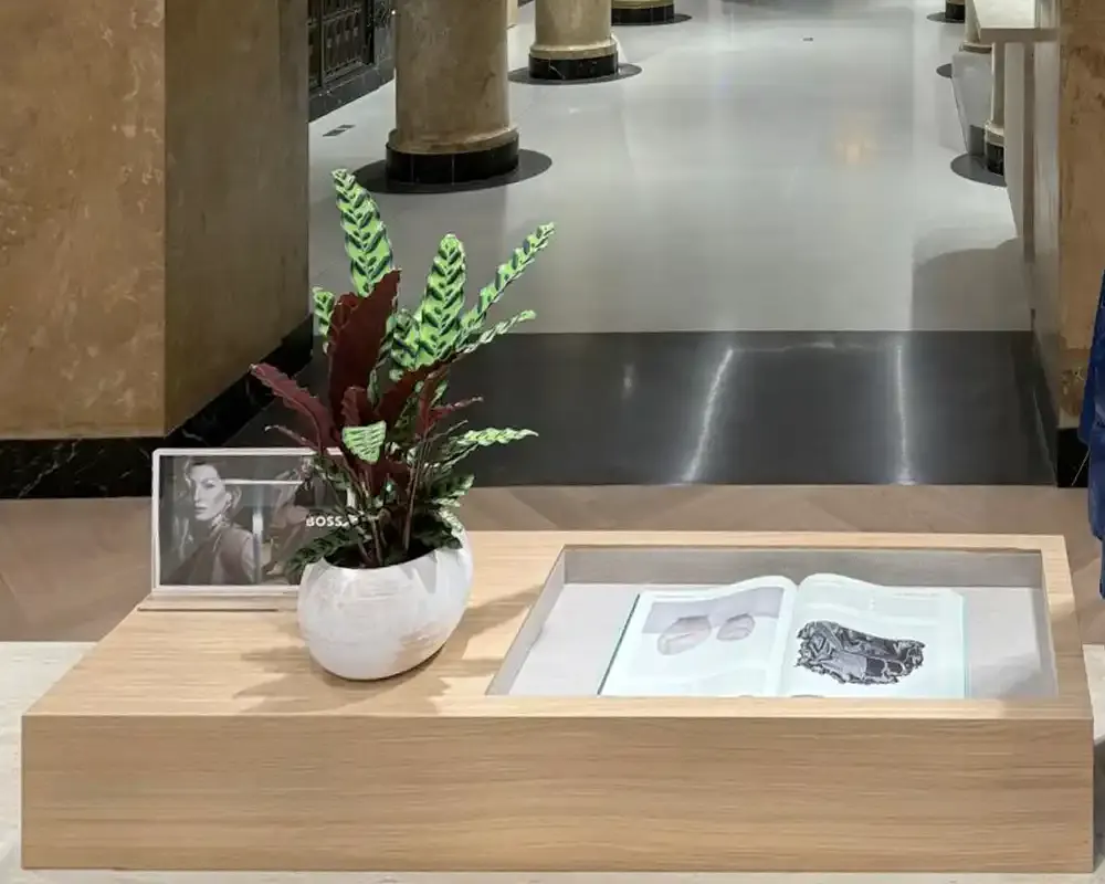 Interior de tienda Hugo Boss con pavimento cementoso decorativo y columnas de mármol en un espacio comercial elegante.