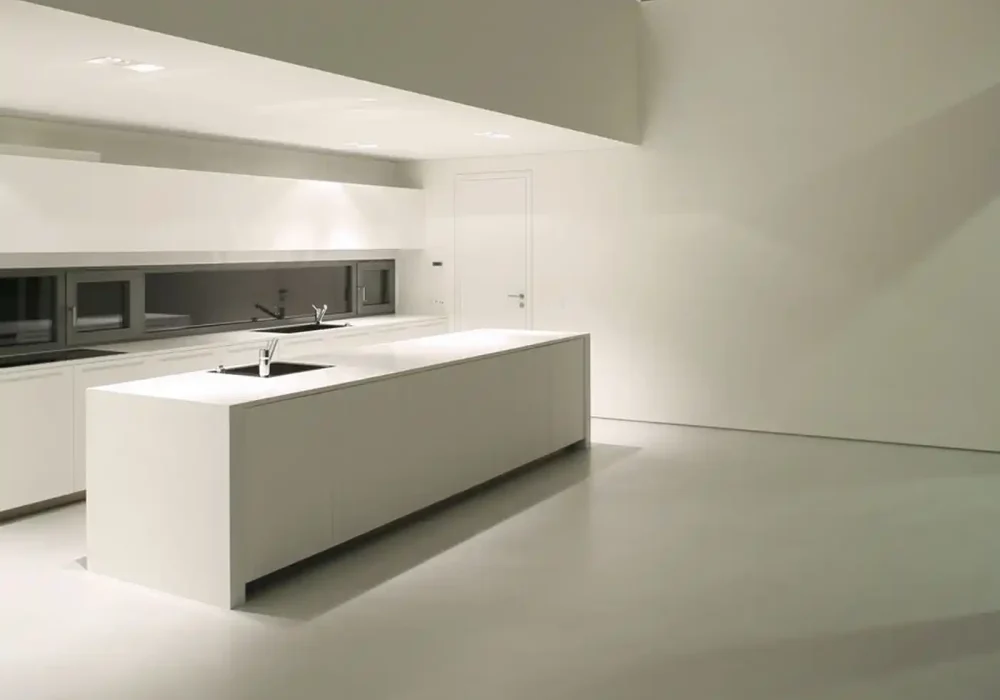 Cocina moderna minimalista con isla blanca y paredes en tonos claros