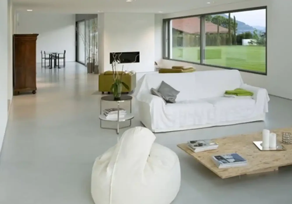 Sala de estar con sofá blanco y ventanales grandes en una casa moderna