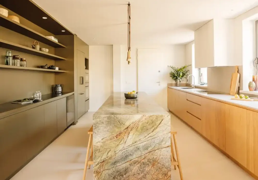 Cocina con isla de mármol, estanterías funcionales y ventanales con vistas al exterior